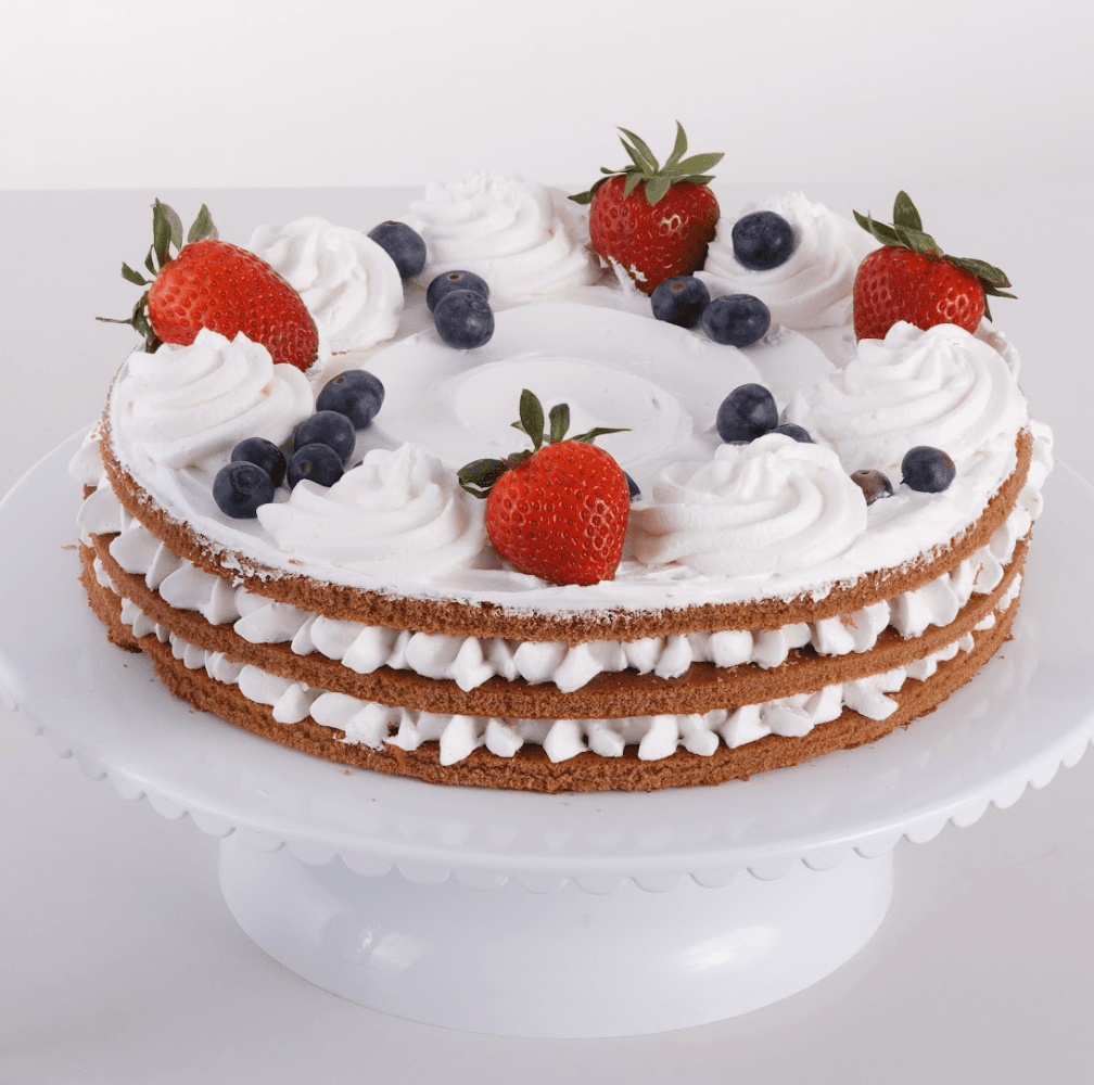 Torta sa ružicama od šlaga, ukrašena jagodama i borovnicama